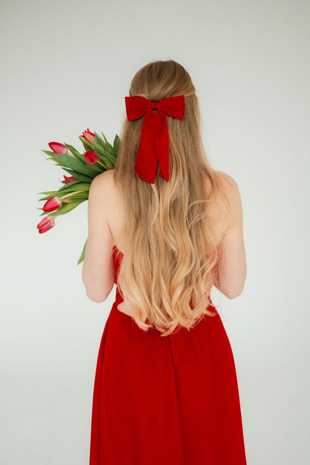 Elegantný detailný pohľad zozadu na ženské vlasy s červenou mašľou a kyticou tulipánov. Fotograf pre Žilinský kraj.