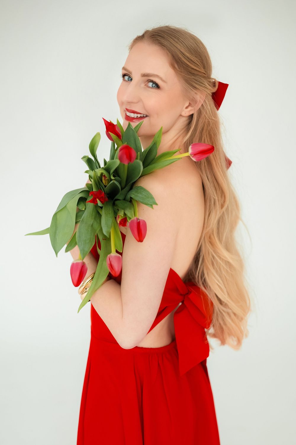 Portrét usmiatej ženy v elegantných červených šatách s kyticou jarných tulipánov. Ateliérová fotografia, Žilina a okolie.