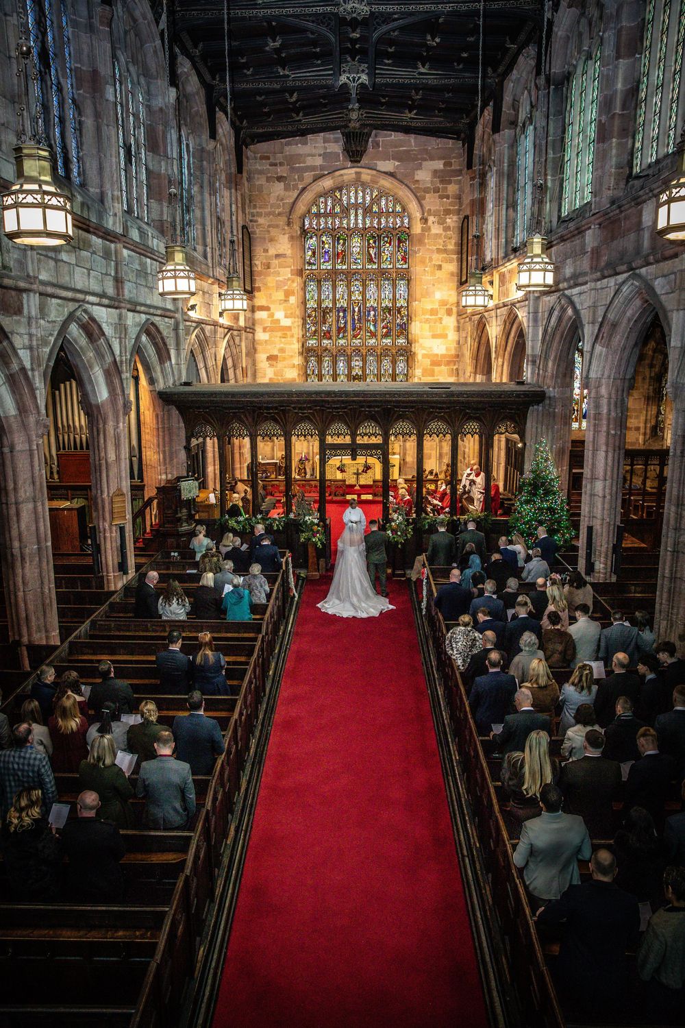 Aerial view of bride walking down red carpet aisle in magnificent stone Gothic church.