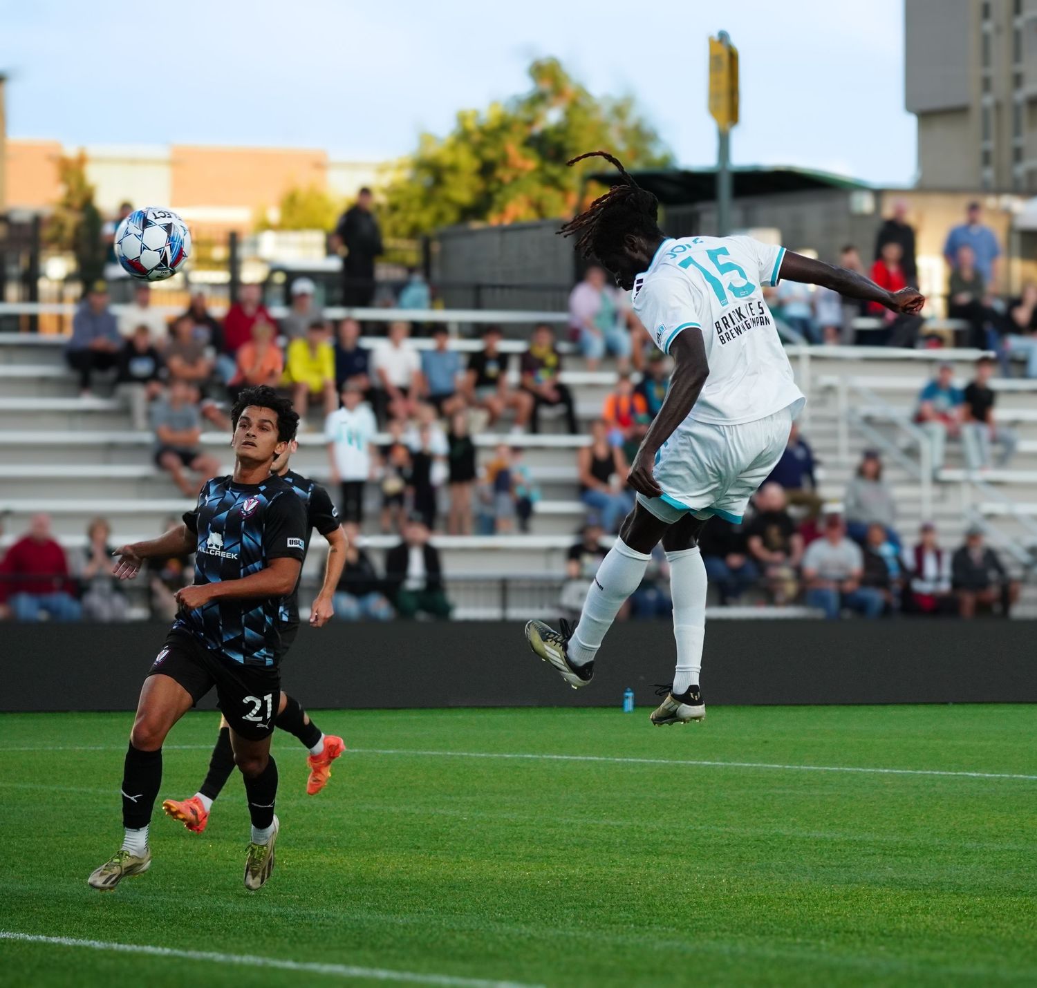 Soccer player performs an acrobatic bicycle kick maneuver on a grass field during a match.