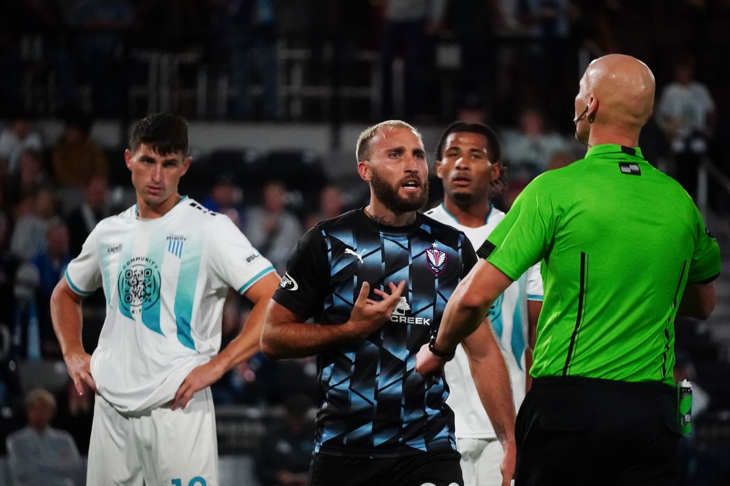 Soccer players in white and light blue striped jerseys compete during an intense match on the field.
