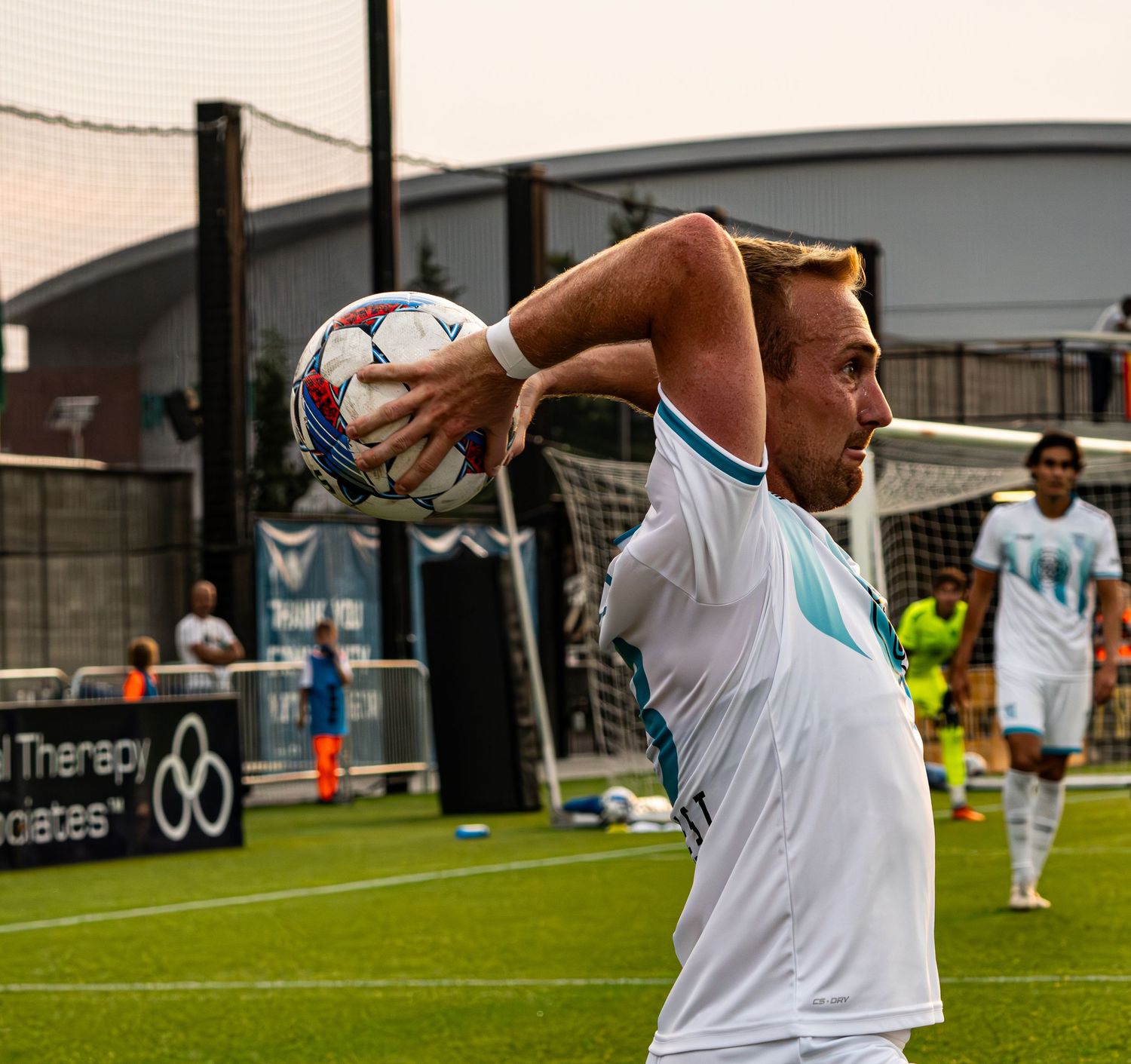 Soccer player performs a throw-in technique on an indoor turf field during practice or training session.