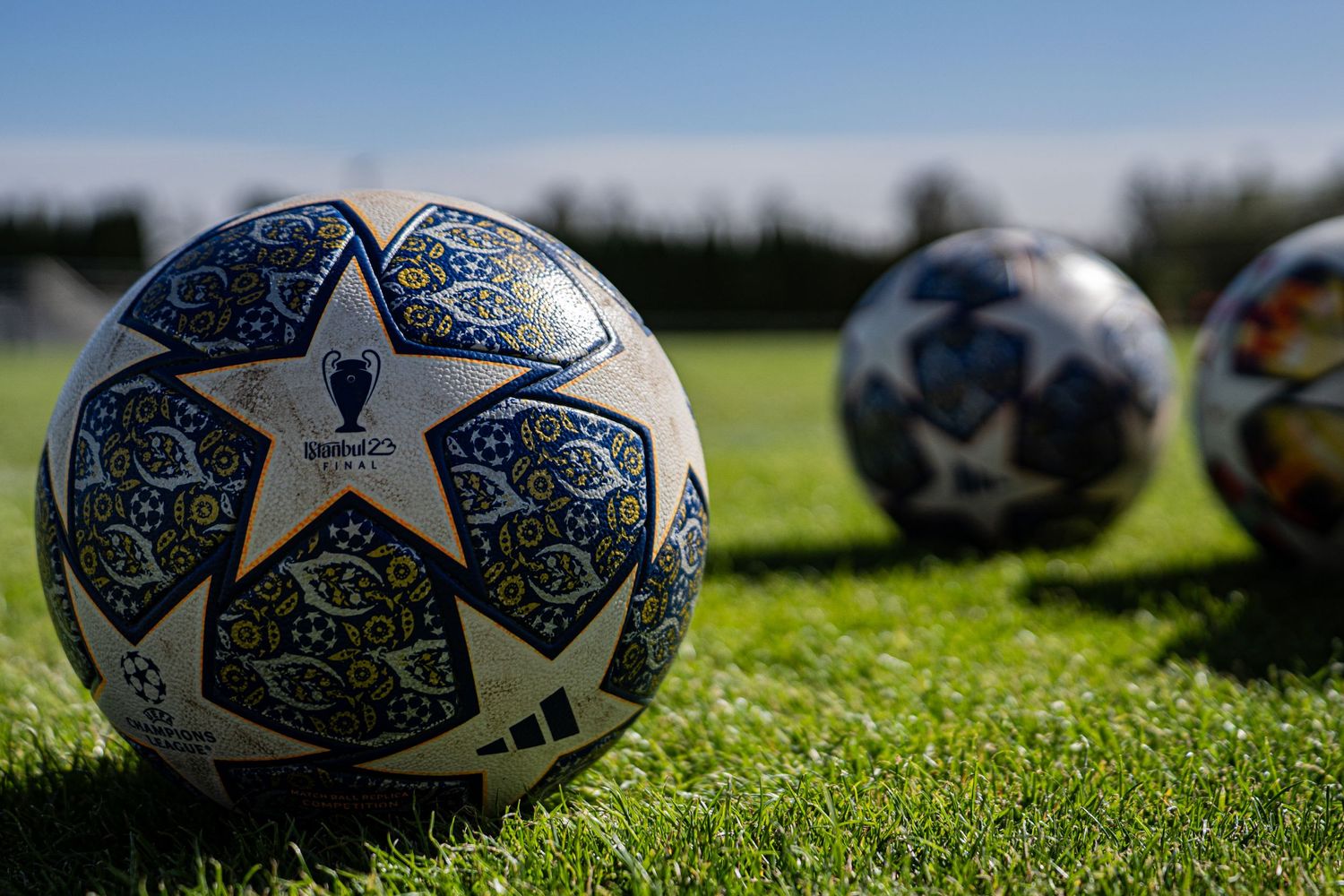 Official UEFA Champions League match balls with distinctive star pattern design lying on grass field.
