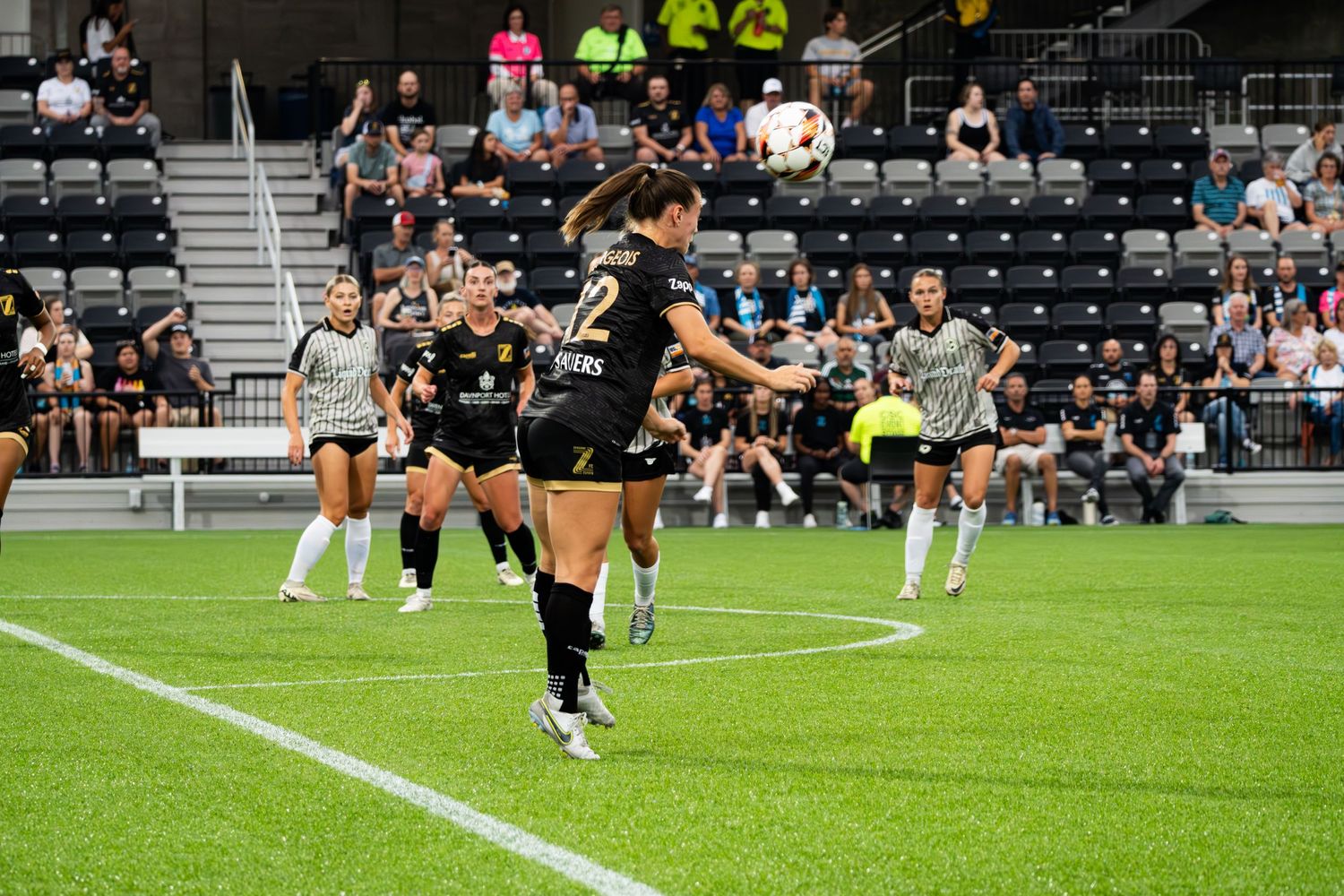 Soccer players leap and celebrate during an intense match on a grass field in a stadium setting.