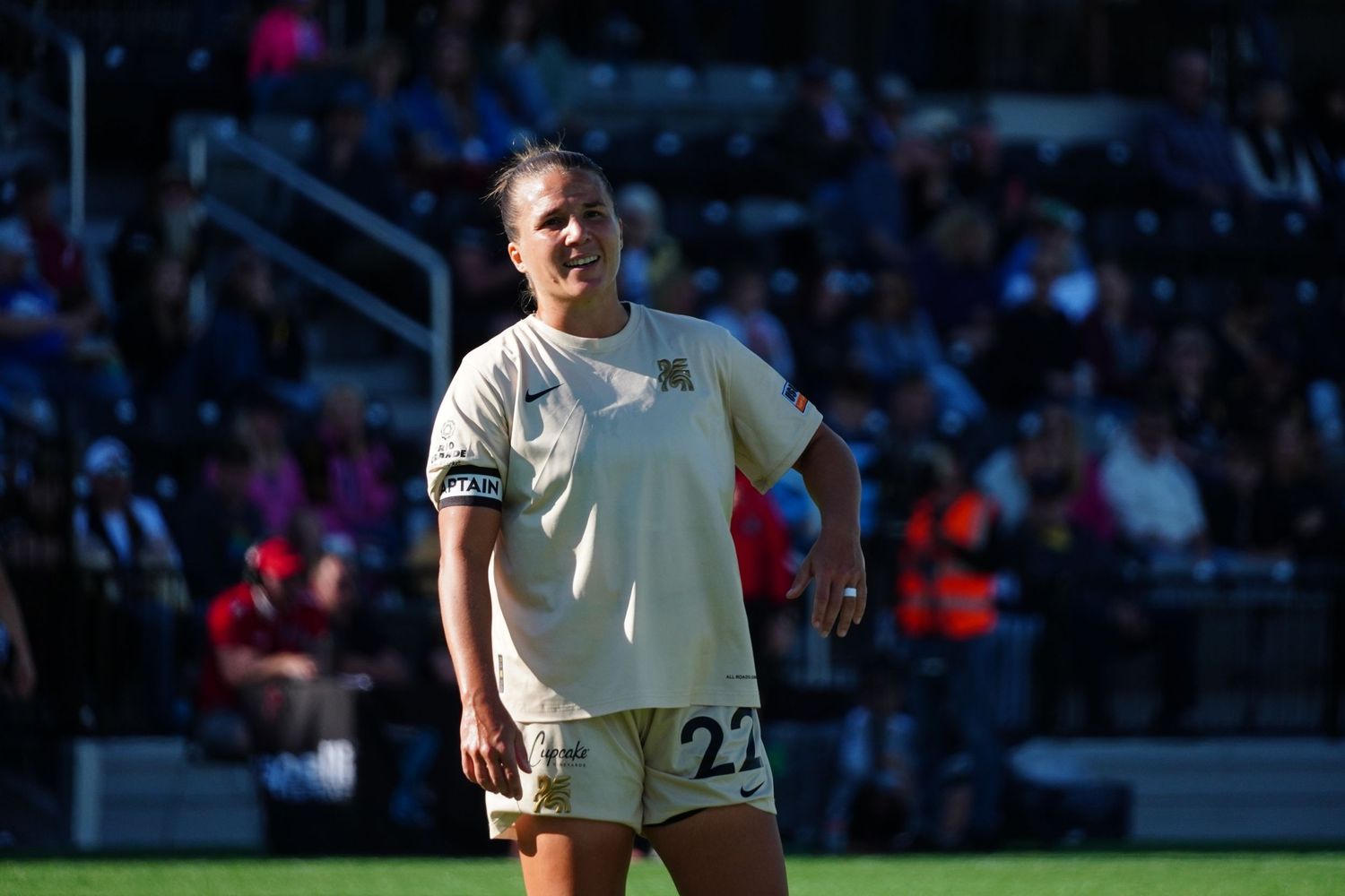 Soccer players in white uniforms compete during a professional match at a stadium filled with spectators.