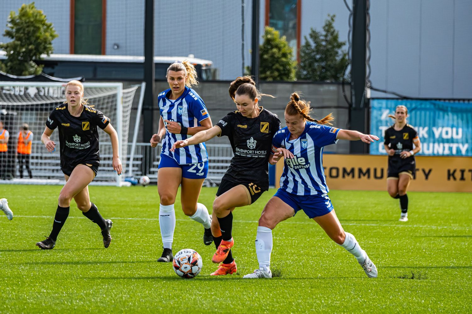 Soccer players in blue and white striped jerseys compete for the ball during an intense match on a grass field.