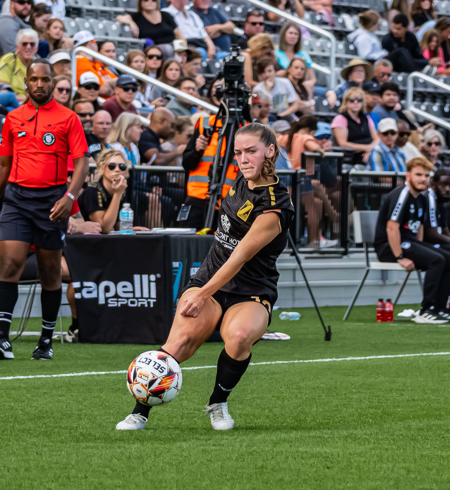 Rugby player attempts a conversion kick during a match with spectators watching from the stands.