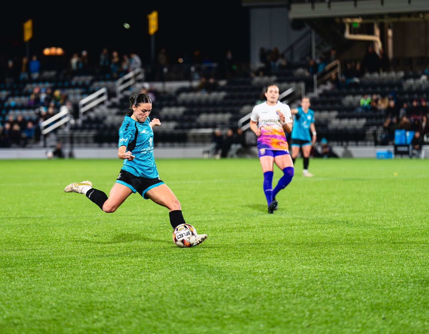 Soccer player in blue uniform sliding on grass field during match action sequence.