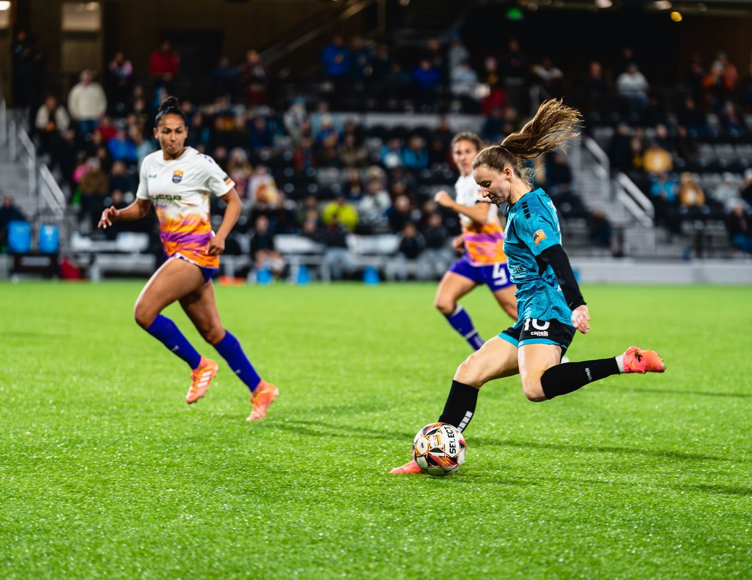 Soccer player slides on grass field to block the ball during competitive match.