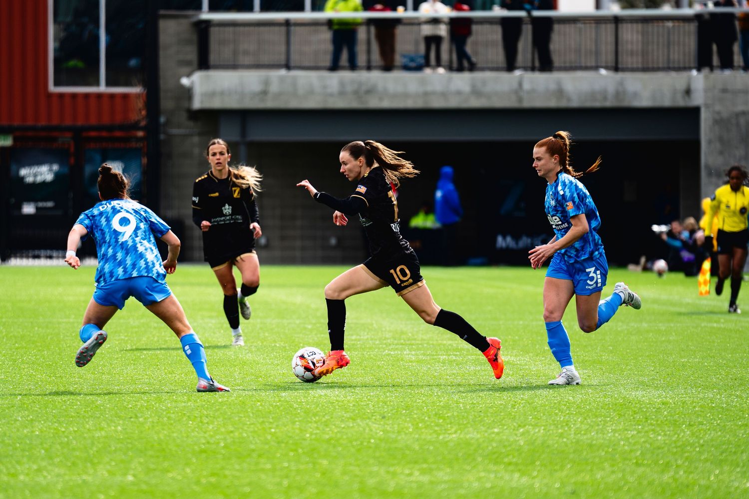 Soccer players compete for possession of the ball during an intense match on a grass field.