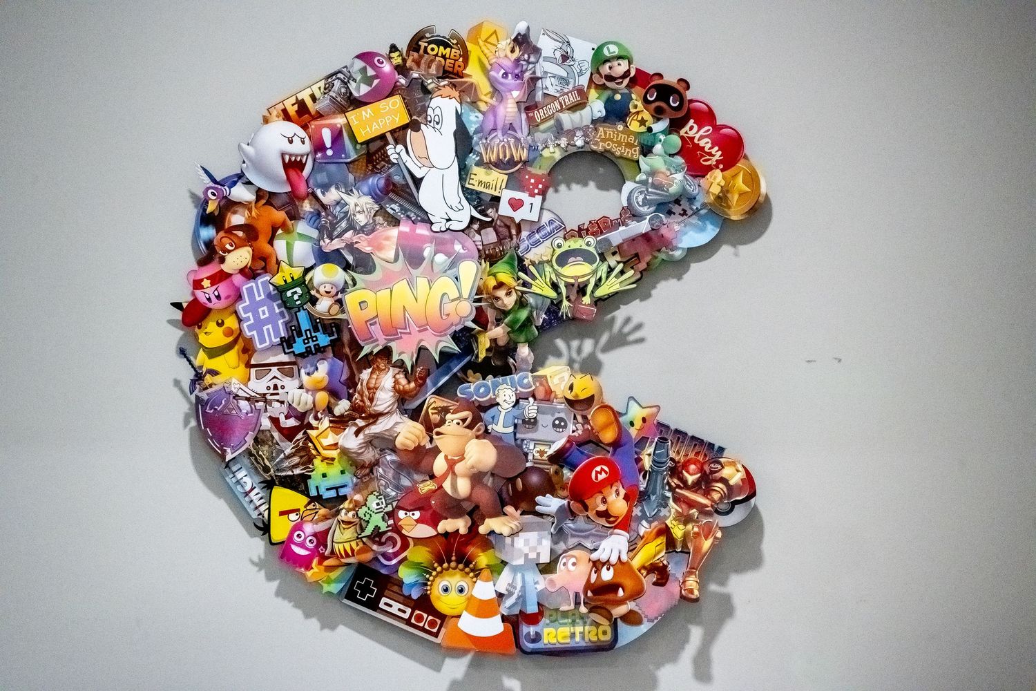 Colorful wall art made from numerous vintage toys and gaming characters arranged in Pac-Man shape.
