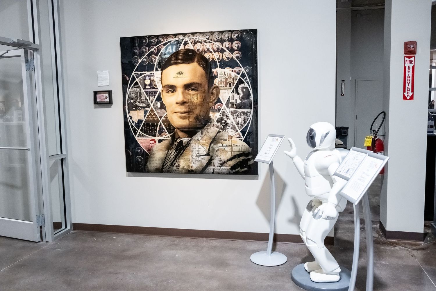 Museum gallery space with modern artwork and white sculptural figure on display.