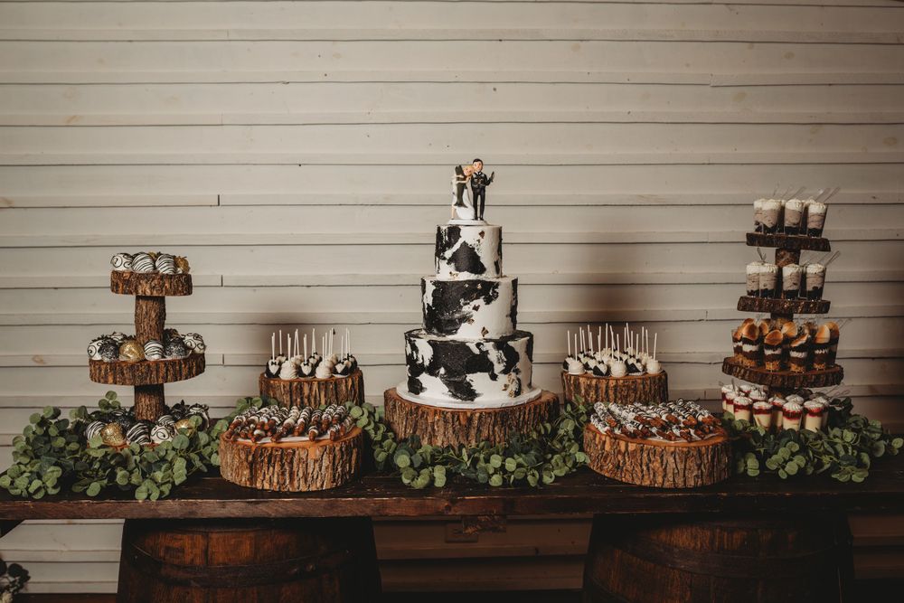 Elegant wedding dessert display featuring tiered cake and cupcakes on rustic wooden table.