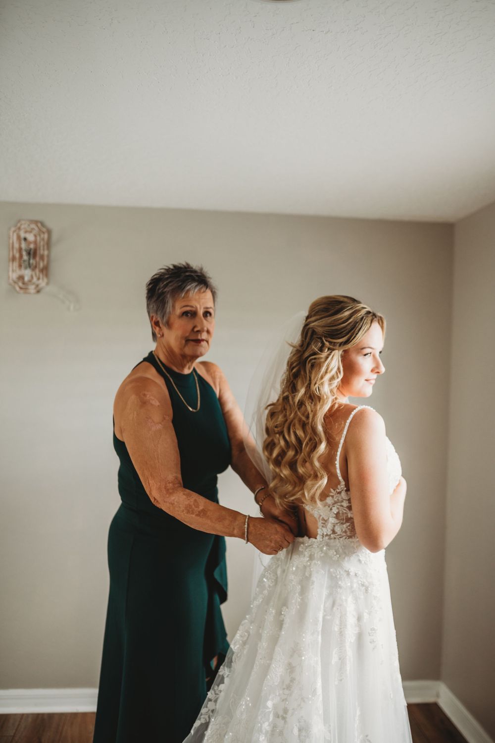 Final adjustments being made to a lace wedding gown before the ceremony.