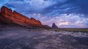 Dramatic sunset clouds over red rock cliffs and desert landscape in American Southwest.