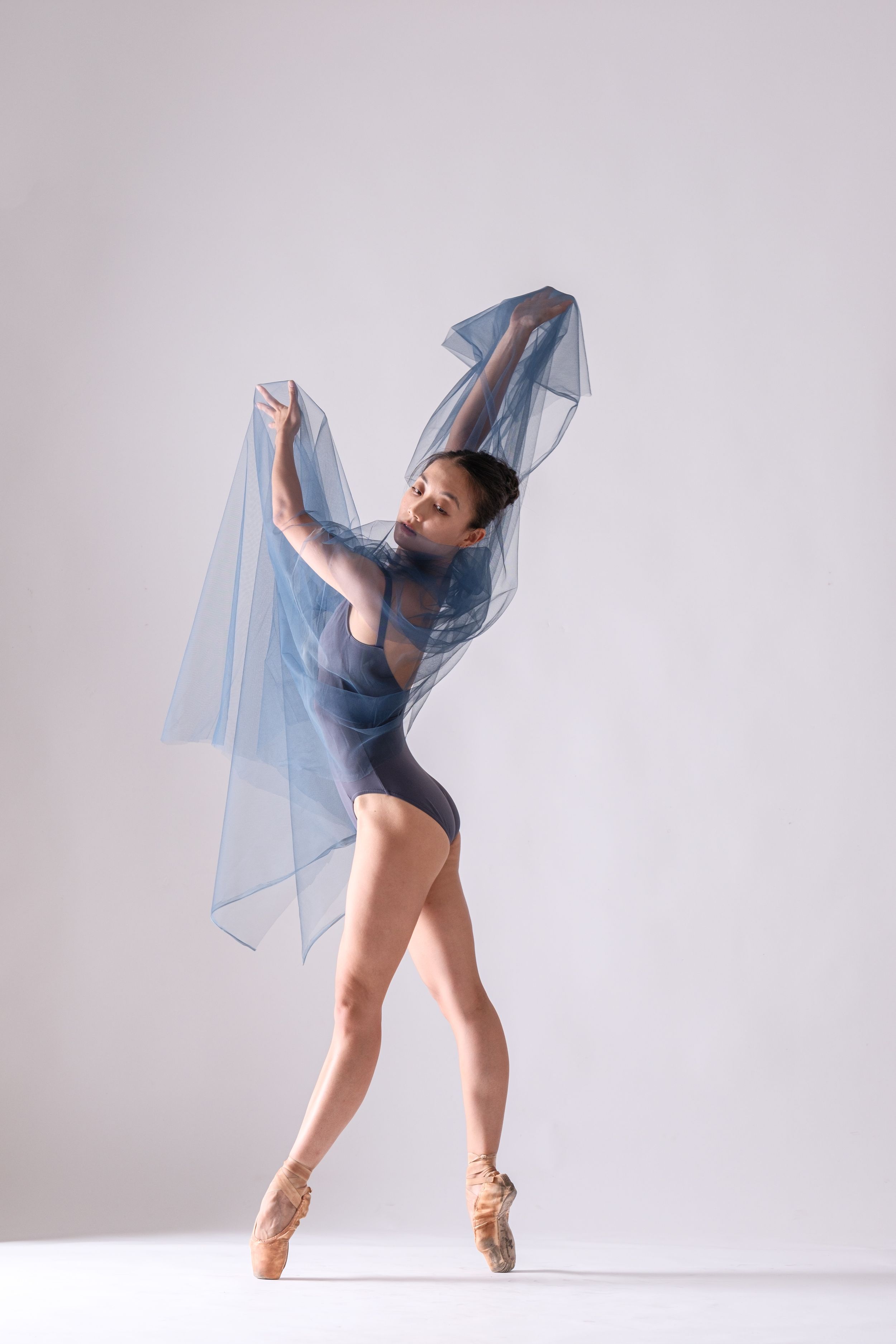 Expressive dance movements with billowing blue fabric in minimalist white space.