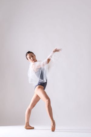 Contemporary dance movement with white fabric creating ethereal effect in studio setting.