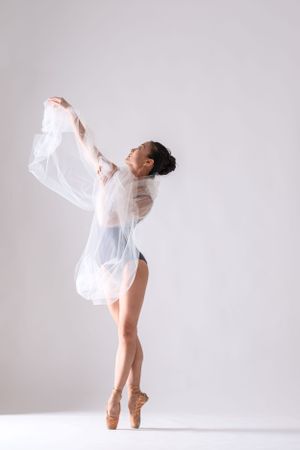 Contemporary dance performance with flowing white fabric against minimalist backdrop.