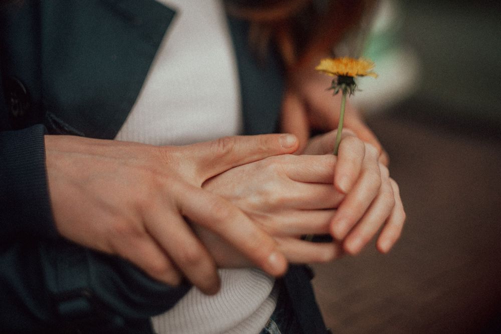 Close-up of hands gently touching in soft natural lighting.