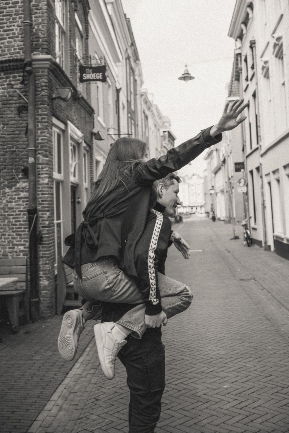 Playful poses captured in black and white on a quaint cobblestone street.