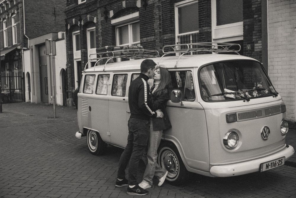 A vintage Volkswagen van parked on a cobblestone street adds retro charm to the urban scene.