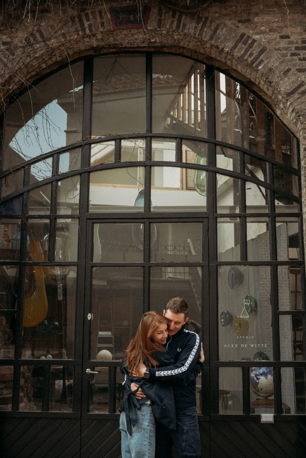 A romantic moment shared beneath brick archways and industrial windows.