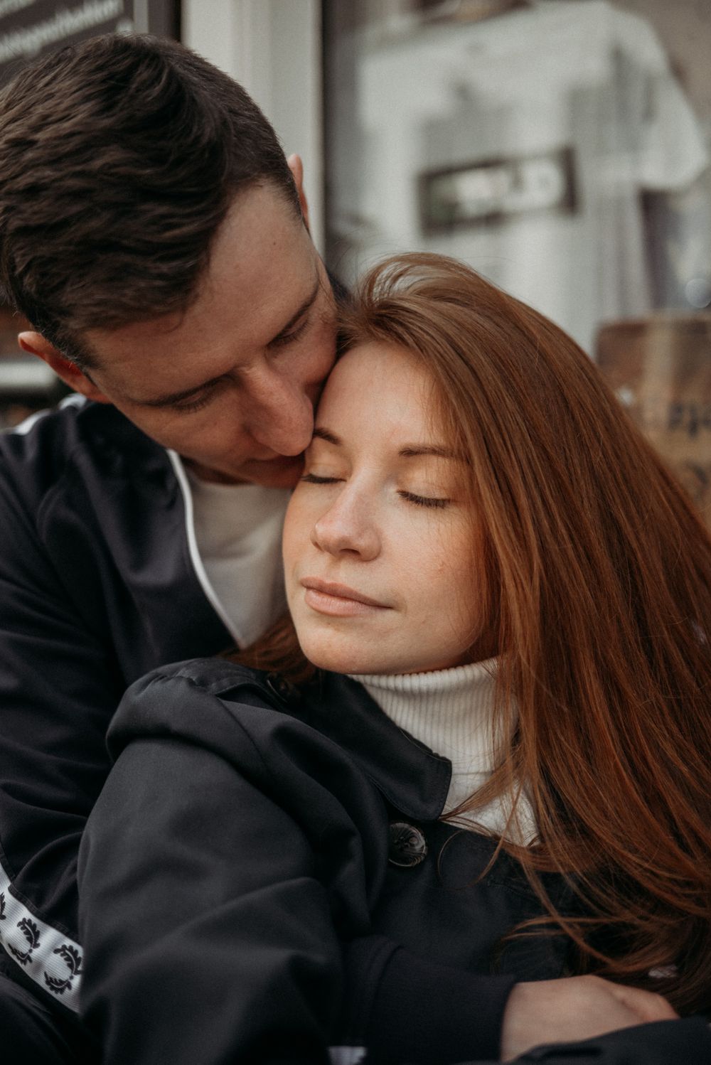 A tender moment shared between a couple in winter clothing.