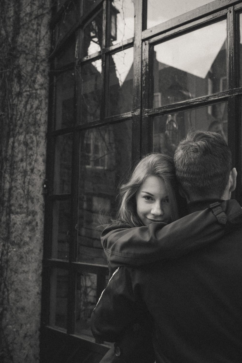 A moody black and white portrait against an industrial window backdrop.