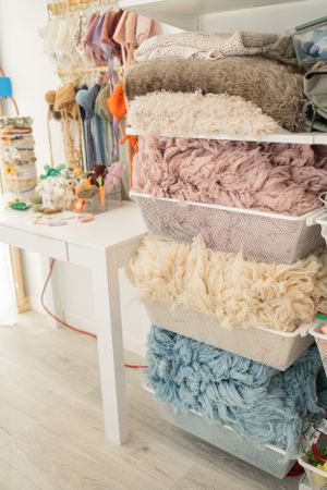 Organized storage bins filled with soft pastel fabrics and textiles in a clean white retail display.