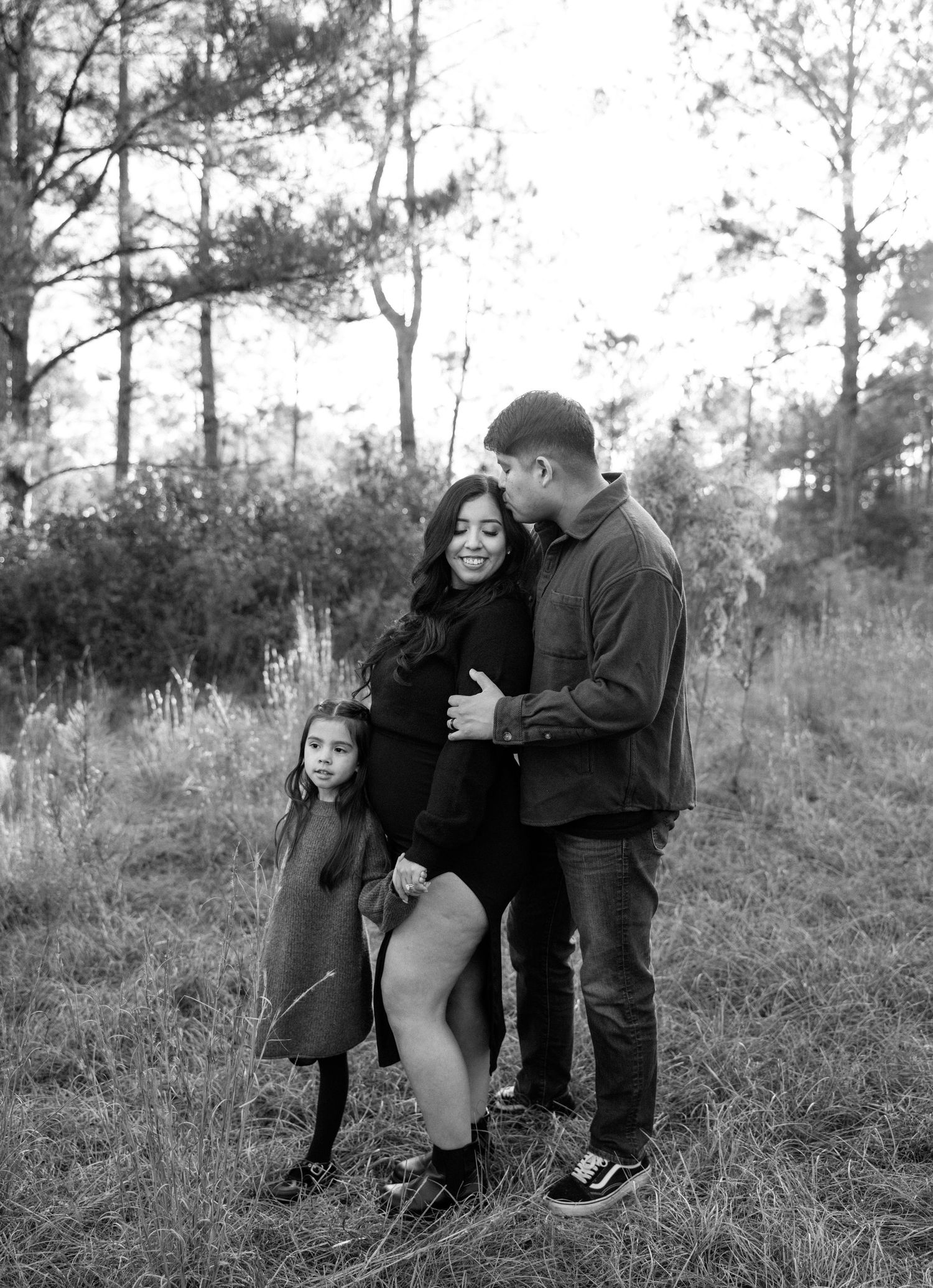 An editorial black and white photo sequence showing a playful outdoor interaction between family members in a wooded setting.