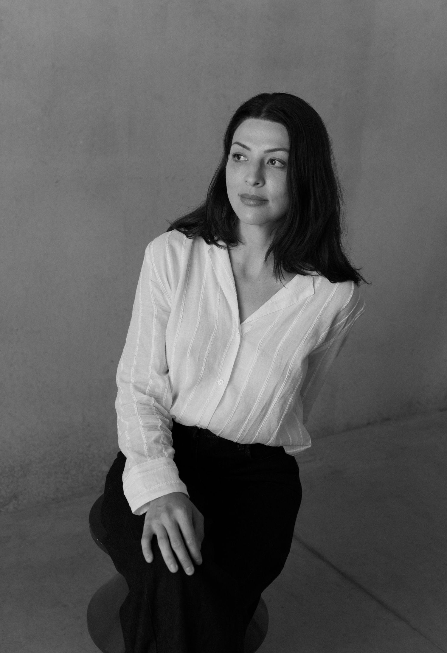 Black and white portrait showing dark-haired person in black clothing against neutral background.