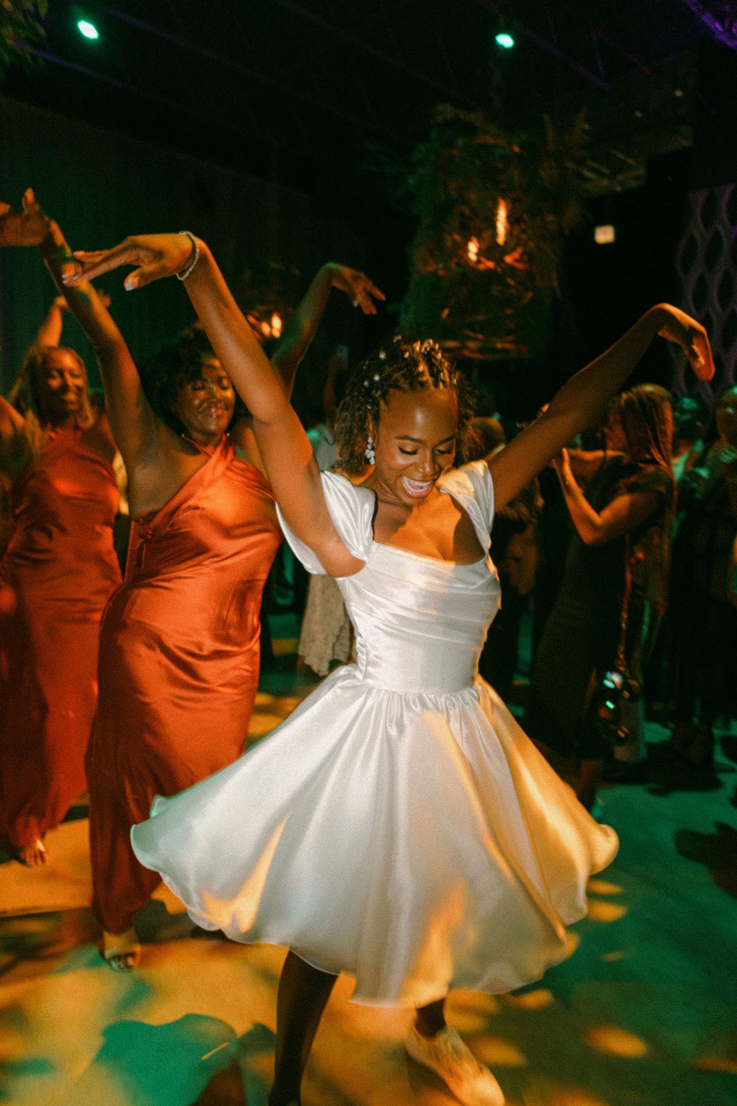 A joyful bride twirling in her short white dress on the dance floor.