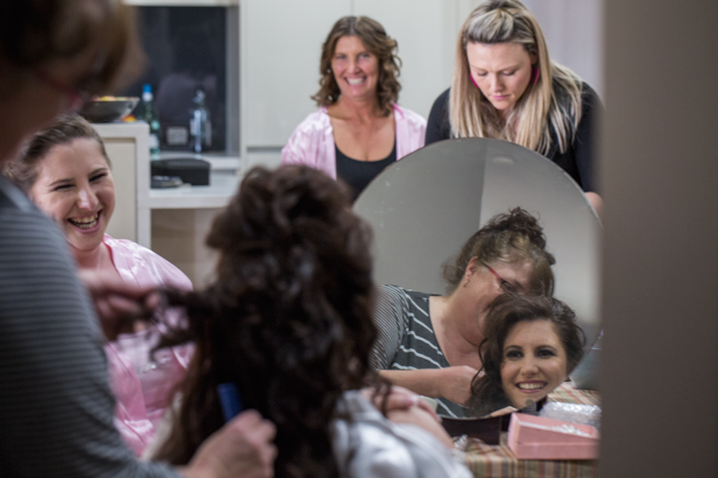 A group gathers around a mirror in preparation for an event.