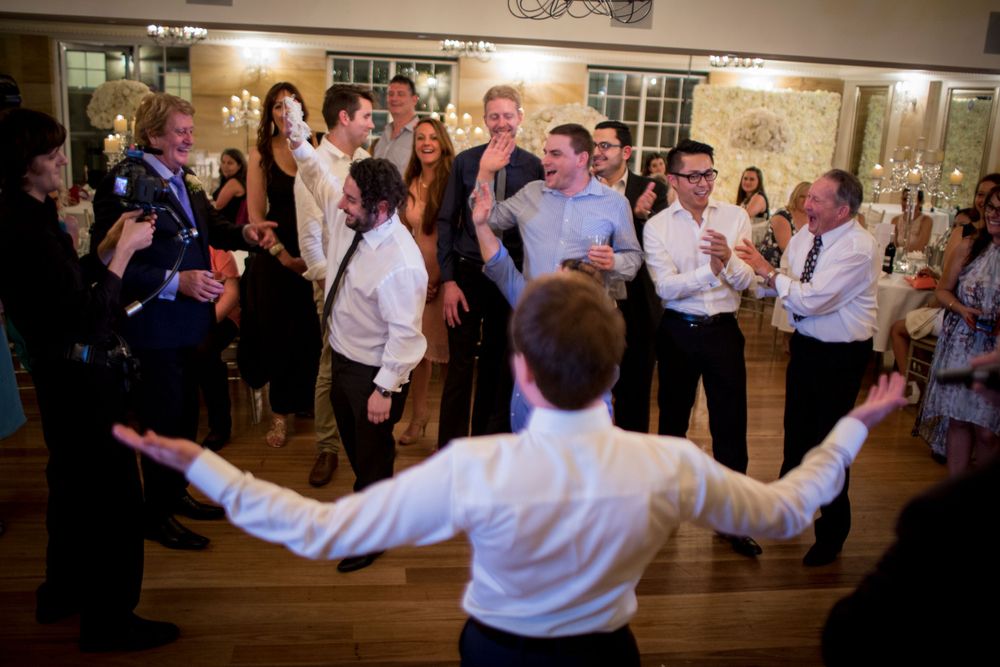 A lively dance celebration on a wooden floor at a reception event.