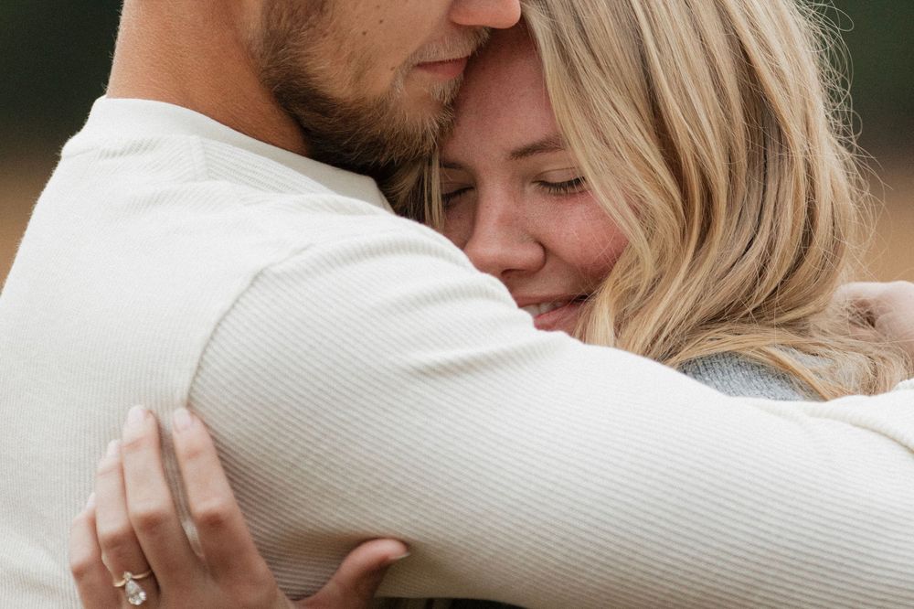 Intimate close-up of couple embracing in white sweaters.