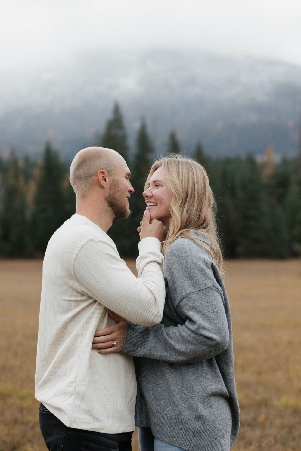 An intimate moment between a couple laughing together in an autumn mountain setting.