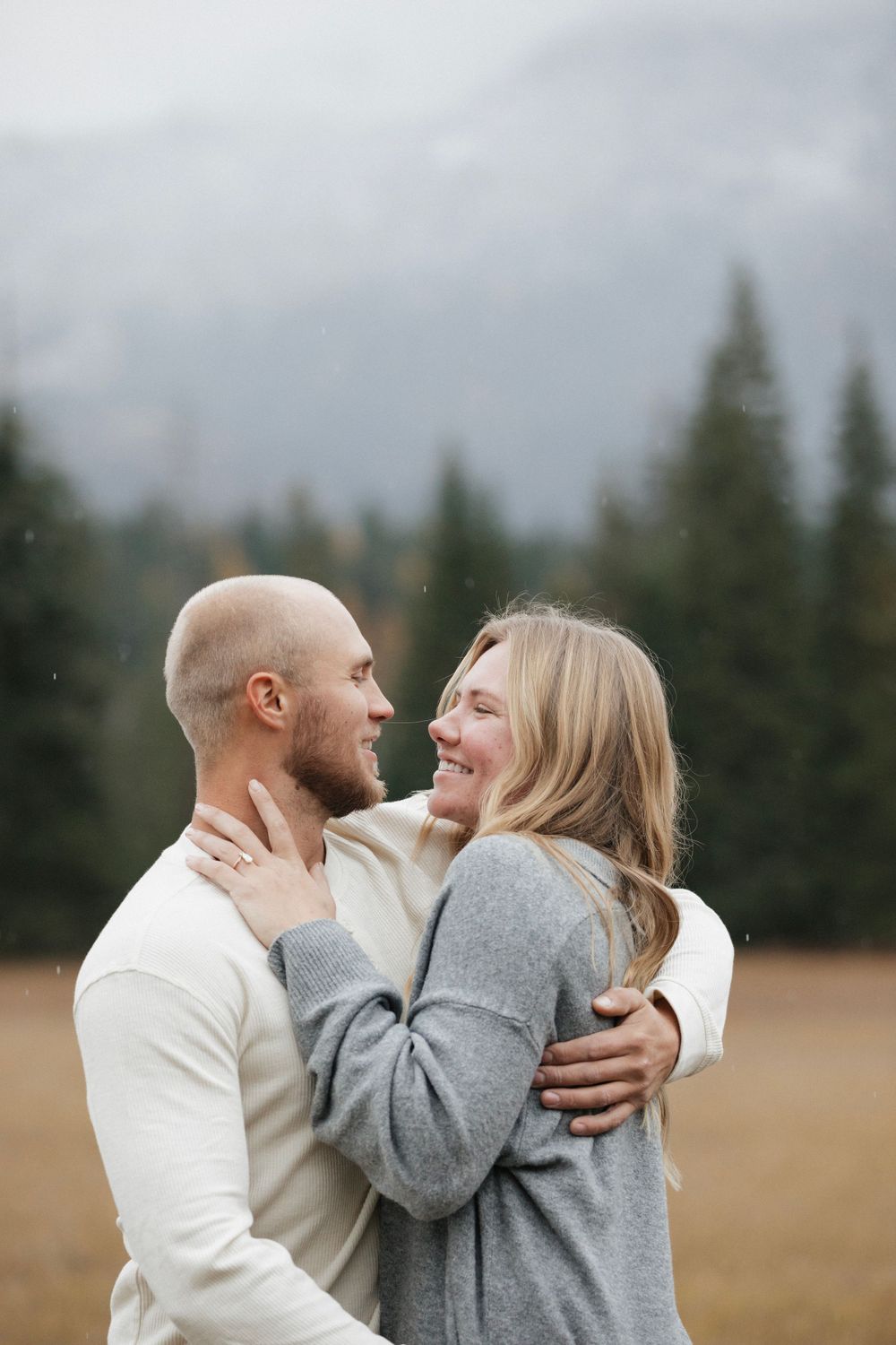 A joyful couple sharing a candid laughing moment in an outdoor mountain setting.