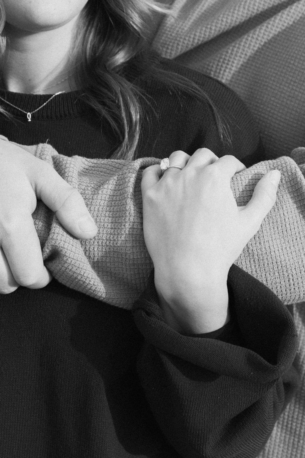 Close-up of hands grasping a gray sweater showing intimate connection.