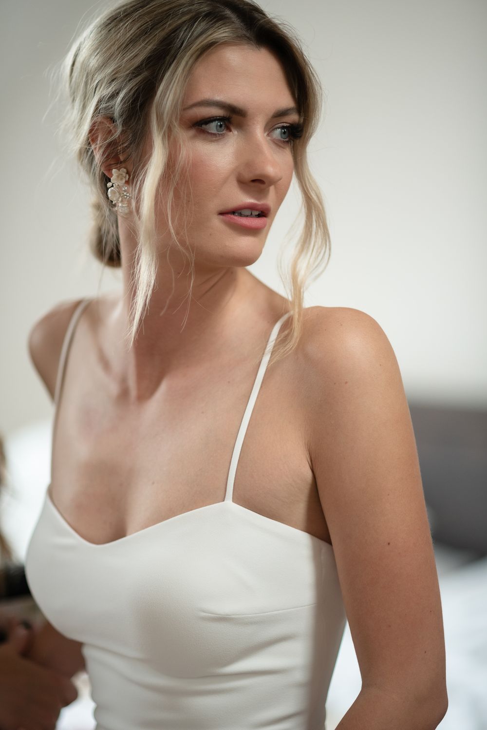 Elegant bride in white dress with soft updo hairstyle looking to side.