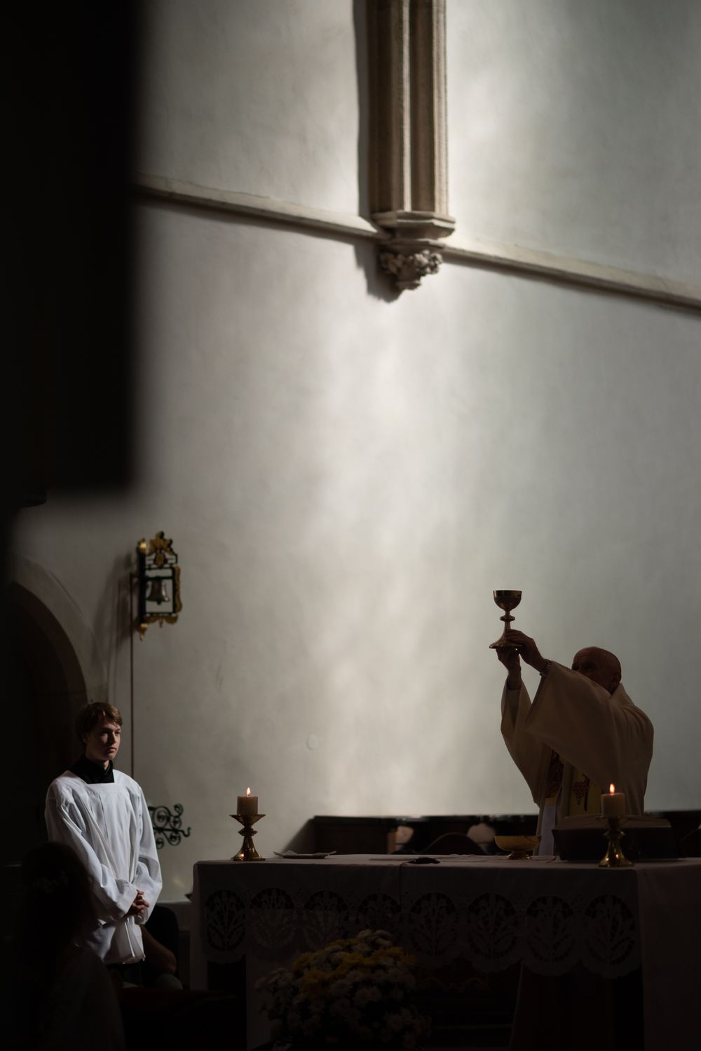 Religious ceremony in dramatic lighting inside historic church interior.
