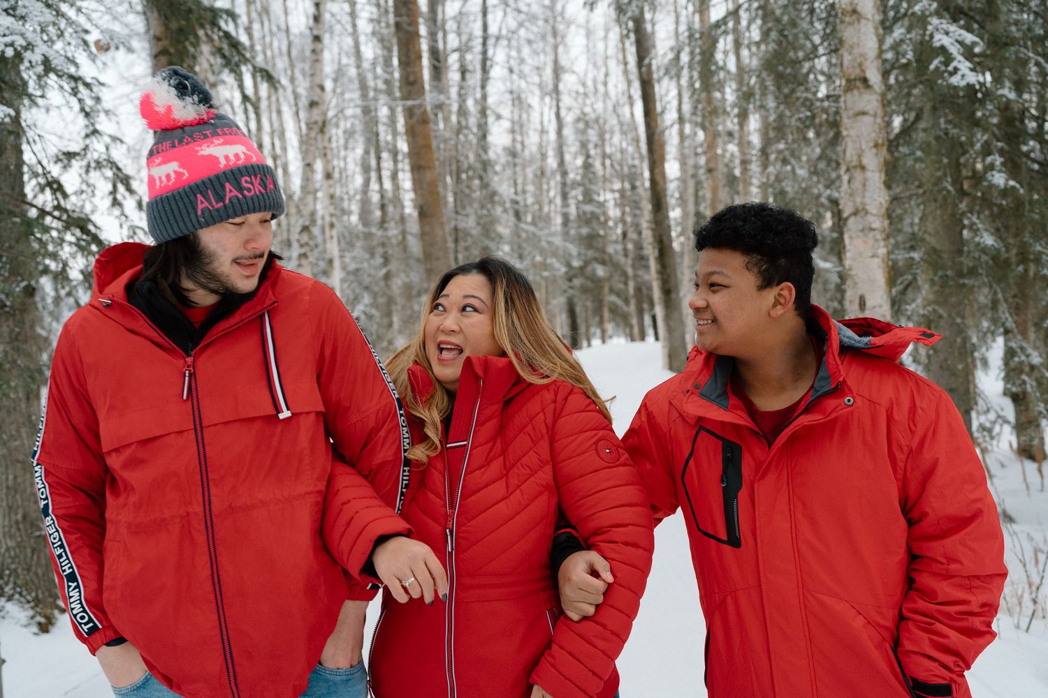 Family in matching red puffers among the beautiful alaska snowy trees