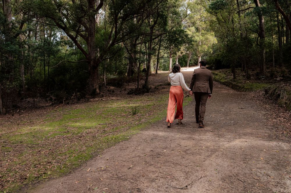 Two people strolling together on a winding forest trail surrounded by lush greenery.