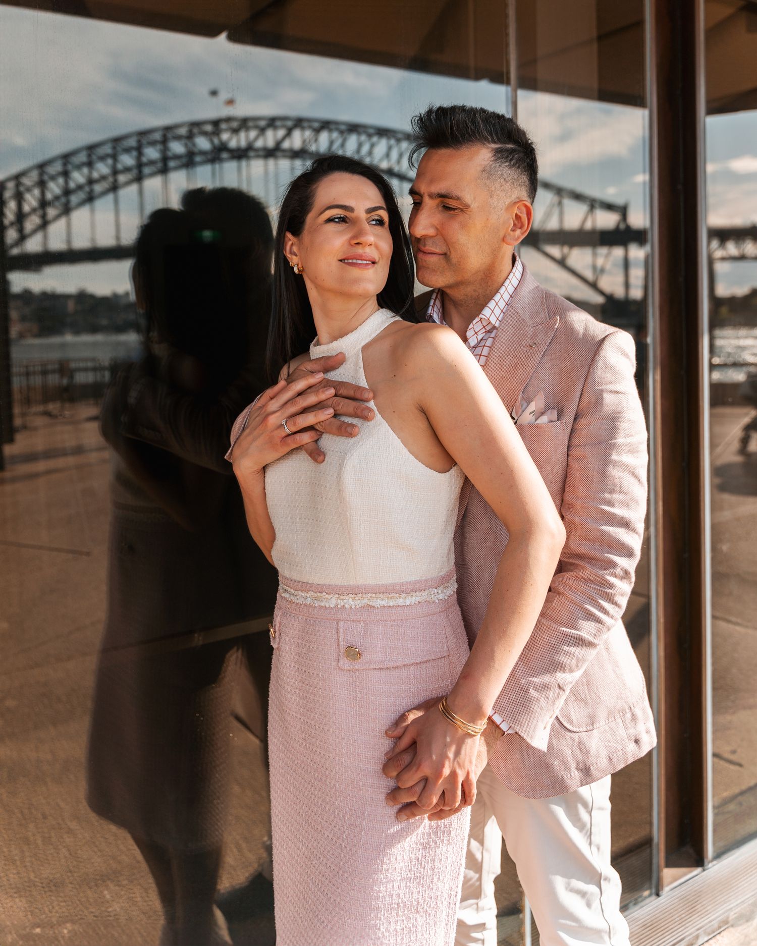 Elegant couple shares intimate moment near harbour bridge during sunset photoshoot.