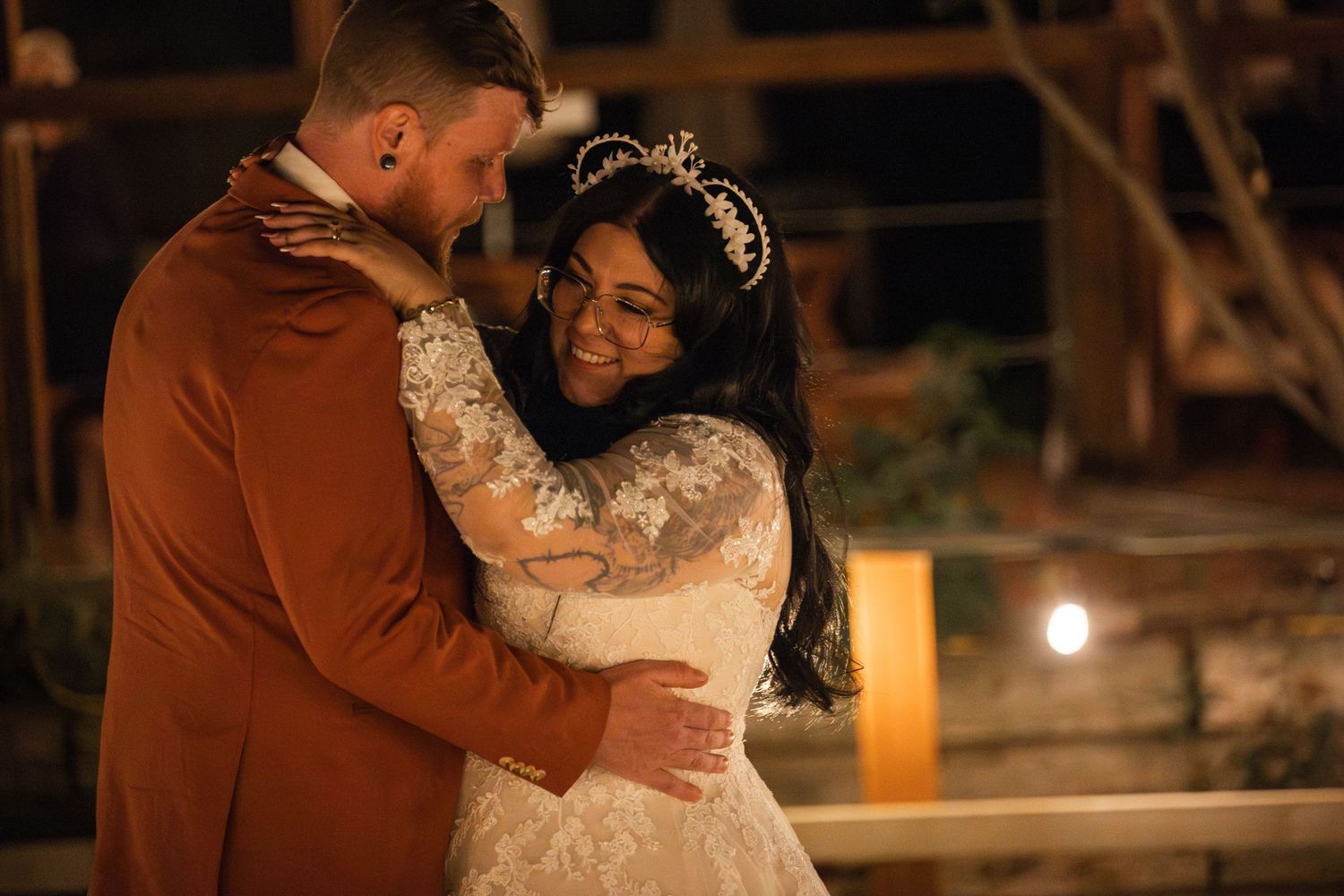 A romantic dance moment at a wedding reception with a rust-colored suit and lace bridal gown.