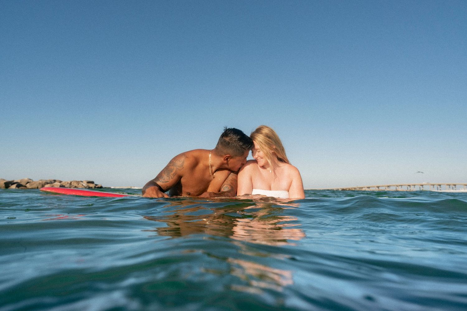 A couple shares a romantic moment floating together in the calm waters of the Destin Jetties, Florida.
