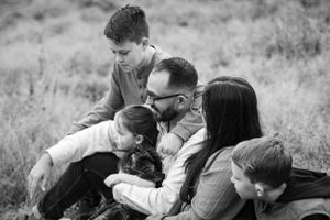 Black and white portrait of a family sharing an intimate moment outdoors.