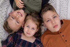 Three siblings lying down together for a playful portrait shot.