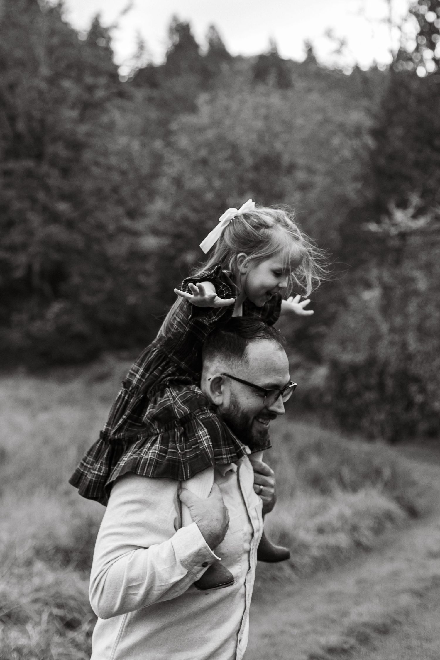 Black and white capture of a joyful piggyback ride on a forest trail.