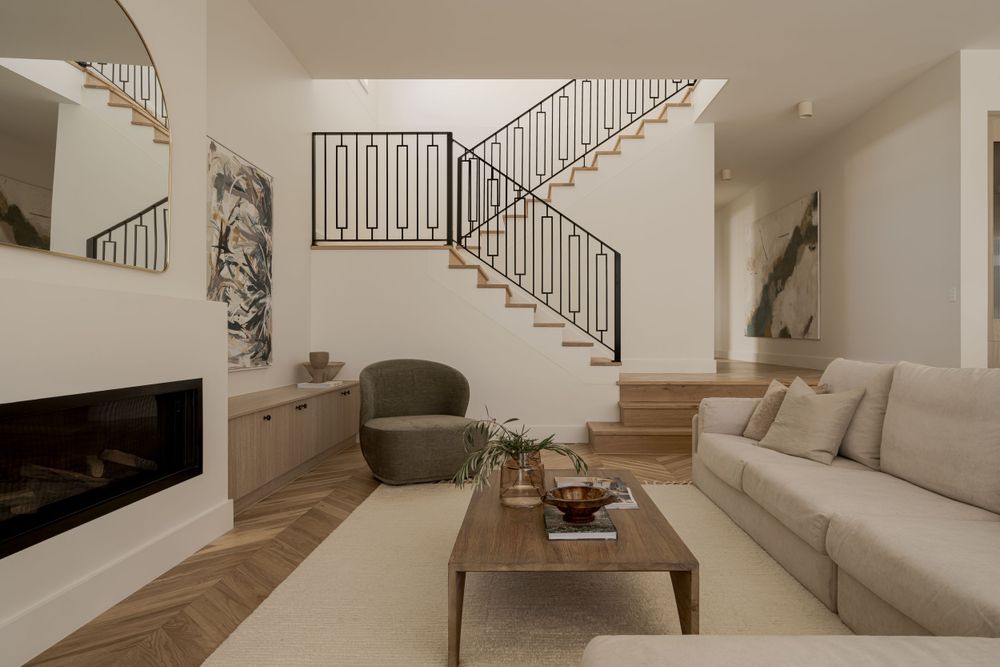 Contemporary living room with floating staircase, built-in fireplace, and neutral furnishings in beige tones.