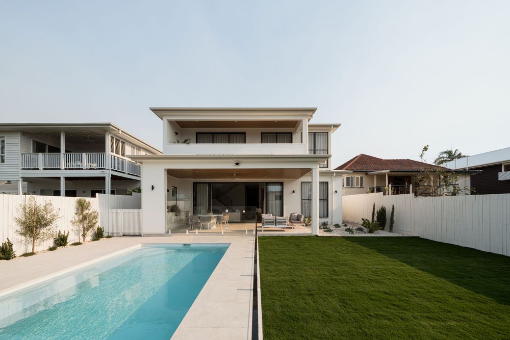 Modern two-story home with a lap pool and artificial turf yard featuring clean architectural lines.
